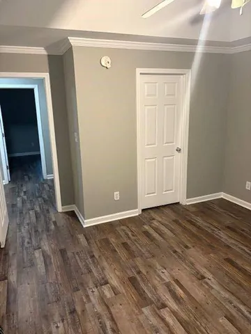 a view of an empty room with wooden floor and closet