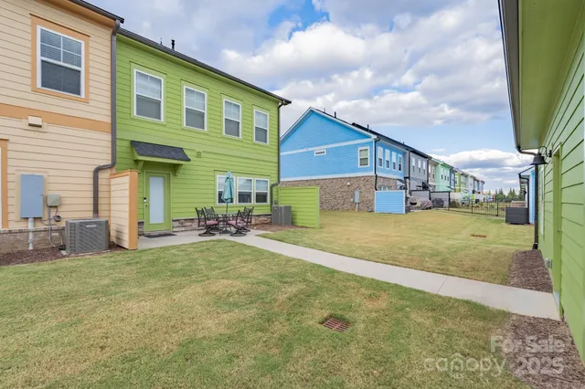 a view of a house with table and chairs next to a yard