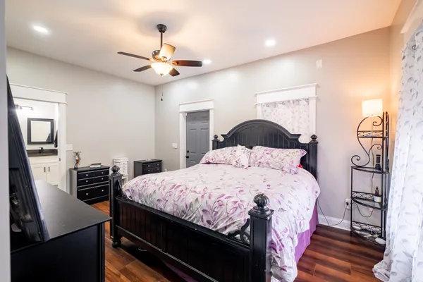 a bedroom with a bed a dresser with wooden floor
