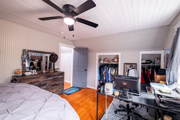 a bedroom with bed a flat tv screen and a bookshelf