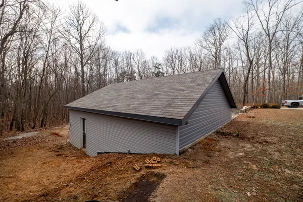 a backyard of a house with large trees and wooden fence