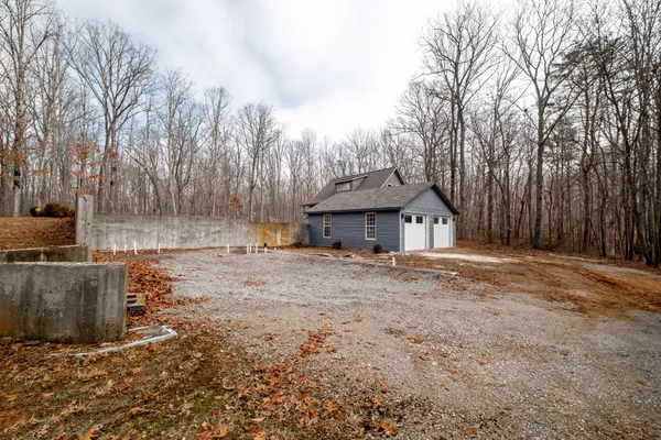 a dirt road with large trees and wooden fence