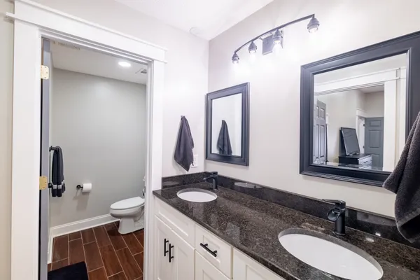 a bathroom with a granite countertop sink toilet and mirror