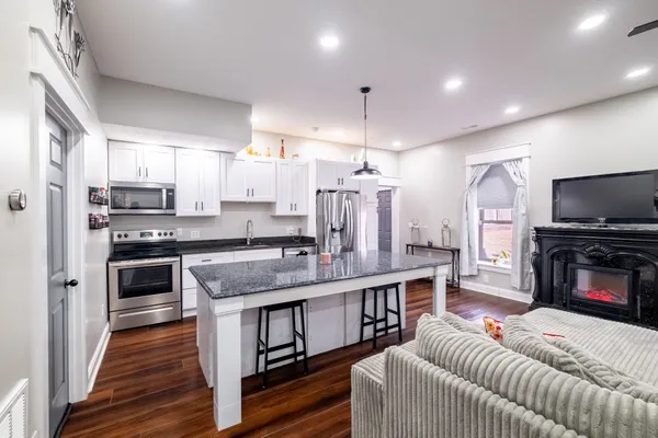 a living room with stainless steel appliances furniture a kitchen view and a fireplace