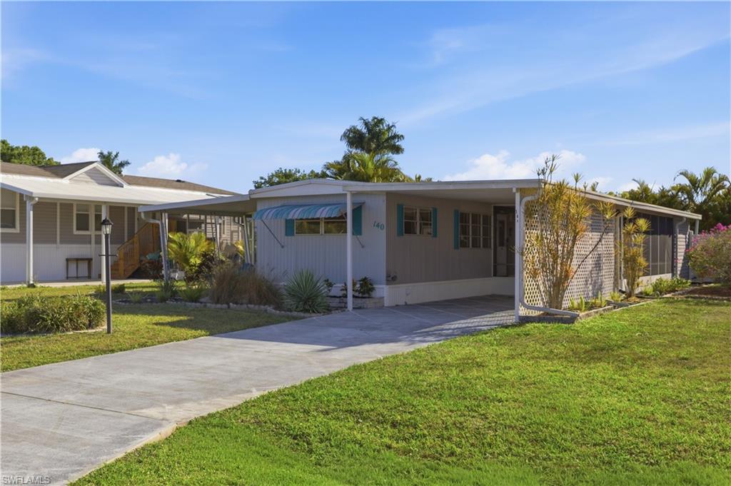 140 Rookery Road Naples, FL 34114 - Photo 2 of 19 View of front facade with an attached carport, concrete driveway, and a front lawn
