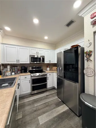 a kitchen with granite countertop a refrigerator and a stove top oven