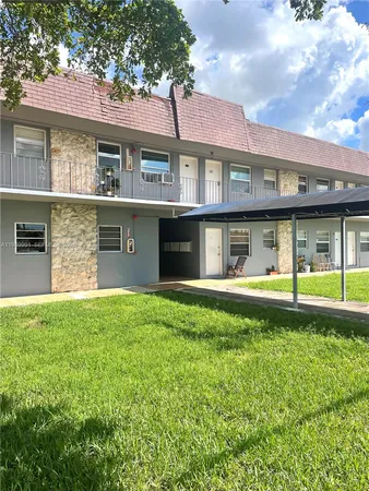 a view of a brick house with a large windows and a big yard and large tree