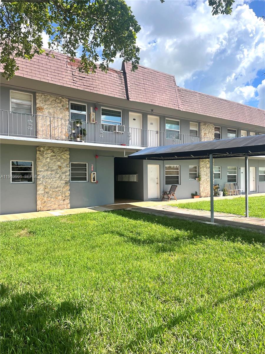 a view of a brick house with a large windows and a big yard and large tree