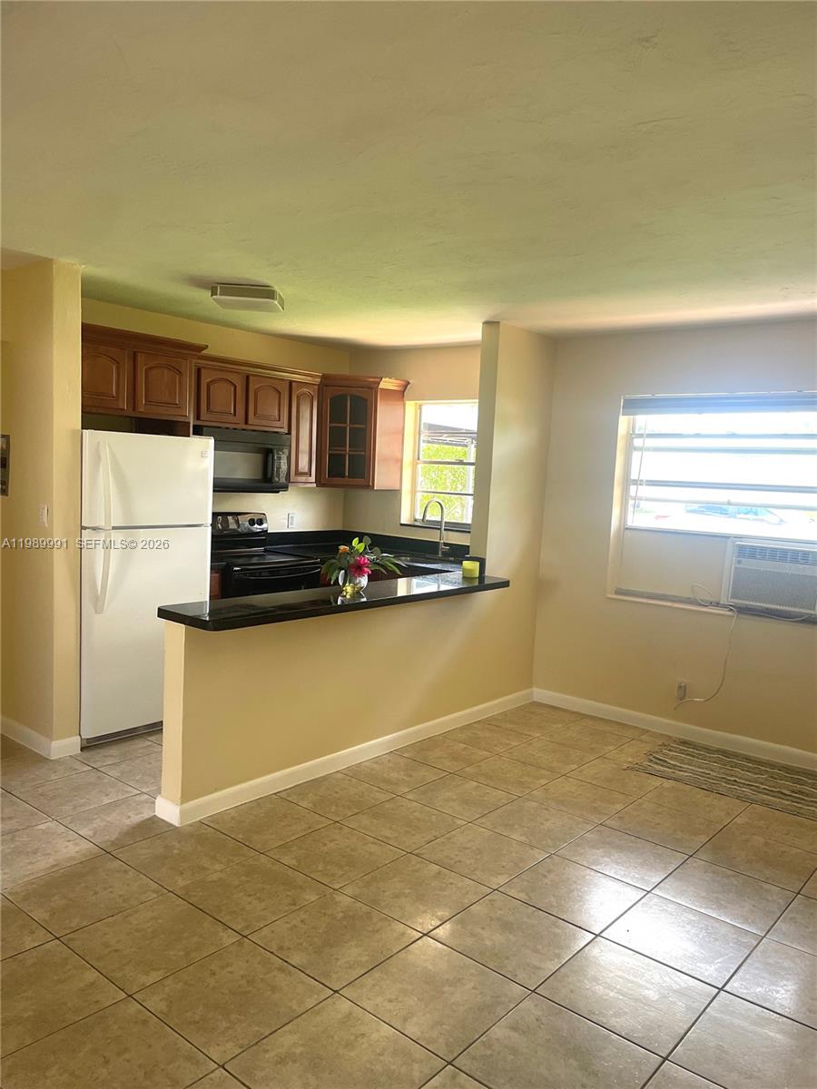 9375 Southwest 40th Terrace, Unit 106 Miami, FL 33165 - Photo 4 of 11 a kitchen with granite countertop a stove a sink and a refrigerator