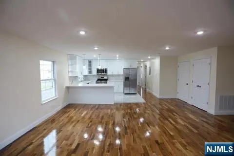 a large kitchen with kitchen island white cabinets and stainless steel appliances