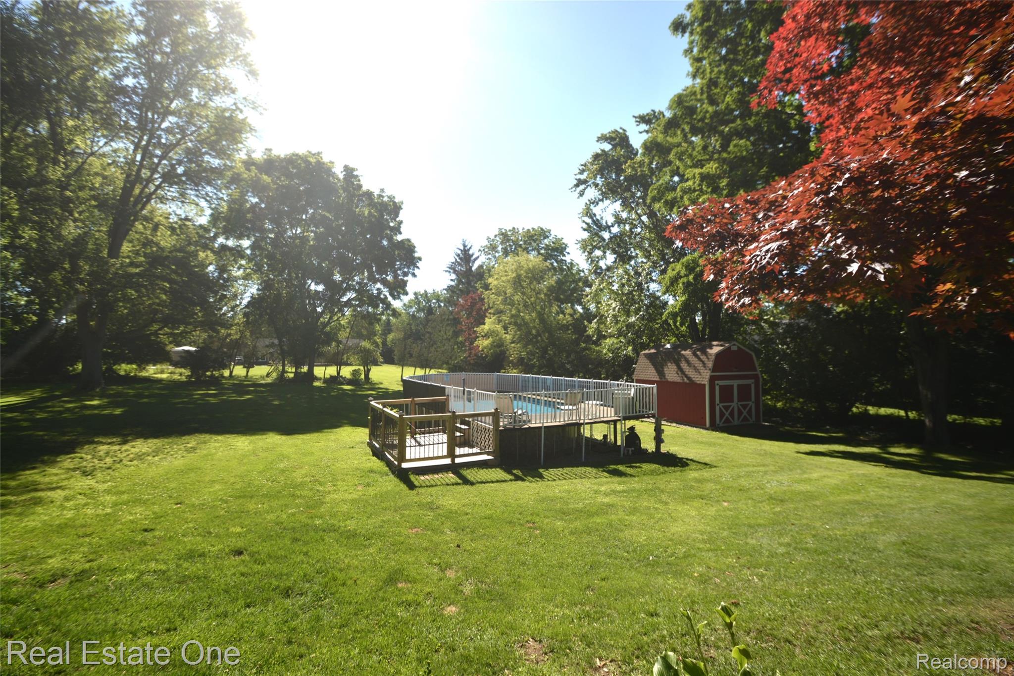 615 Willard Avenue Rochester, MI 48307 - Photo 6 of 30 Expansive green lawn featuring an above-ground pool with a surrounding wood-finish deck and safety railing