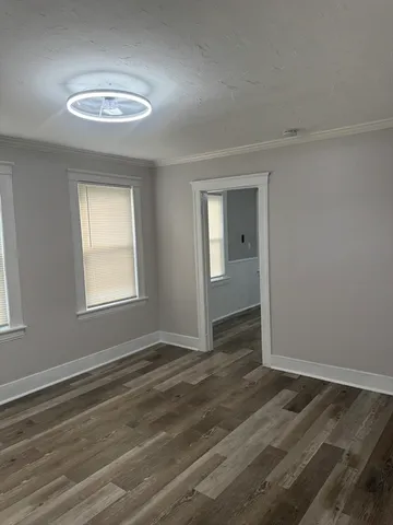 a view of an empty room with wooden floor and a window