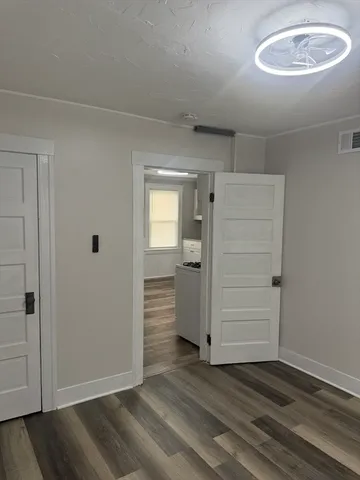 an empty room with wooden floor closet and windows