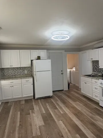 a kitchen with a refrigerator and white cabinets