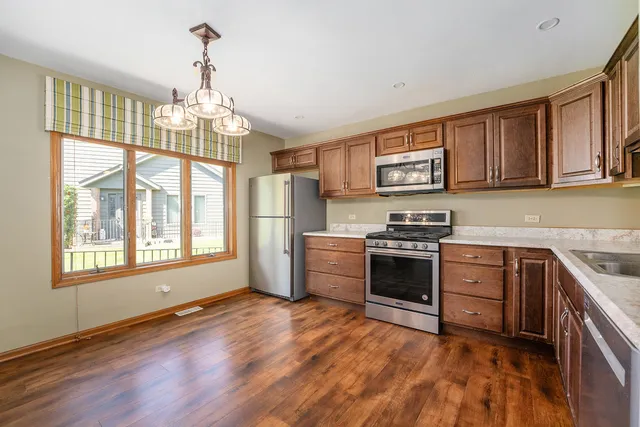 a kitchen with granite countertop wooden floors stainless steel appliances and a window