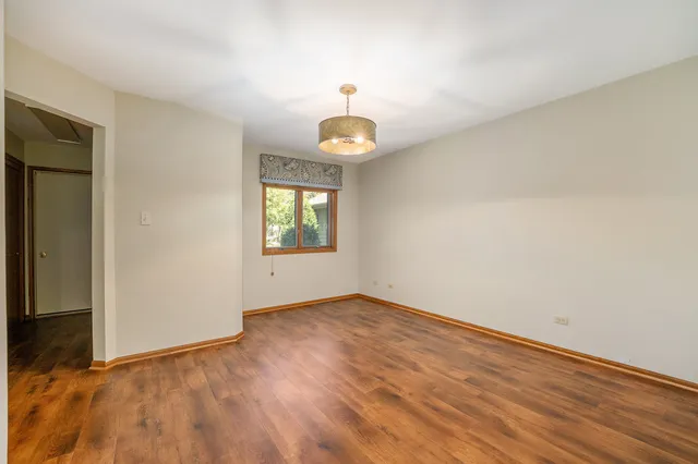 an empty room with wooden floor cabinet and windows