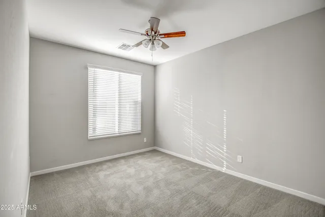 an empty room with closet and a ceiling fan