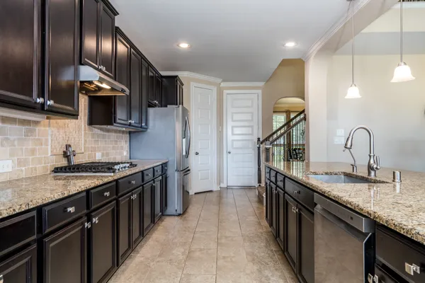 a kitchen with stainless steel appliances granite countertop a sink a stove and a refrigerator