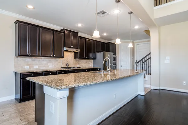 a kitchen with stainless steel appliances granite countertop wooden cabinets a sink and a counter top space