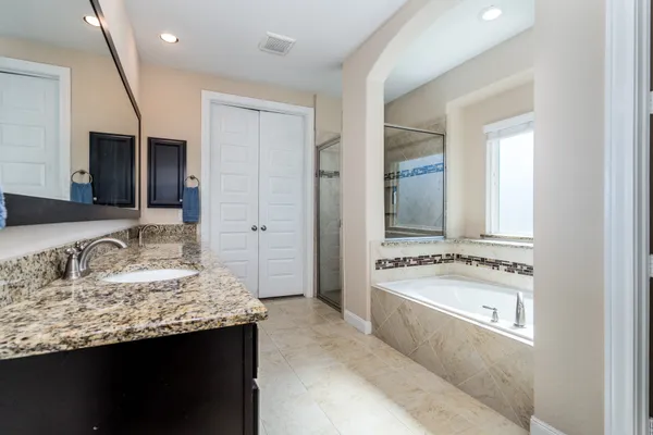 a bathroom with a granite countertop tub sink and mirror