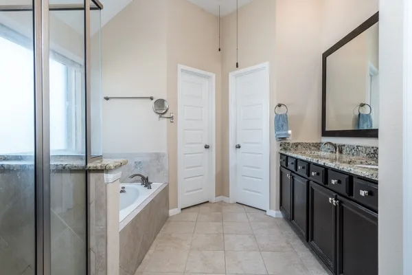 a bathroom with a granite countertop sink a mirror and a bathtub