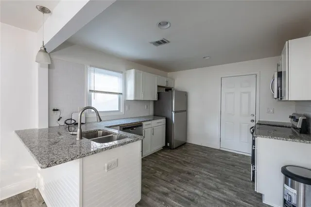a kitchen with granite countertop a sink stove and refrigerator