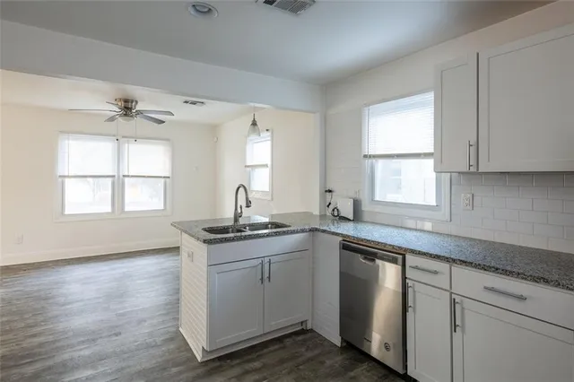 a kitchen with stainless steel appliances granite countertop a sink a stove a window and cabinets