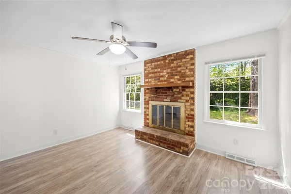 an empty room with wooden floor fan and windows