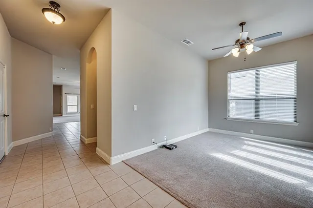 a view of an empty room with window and chandelier fan