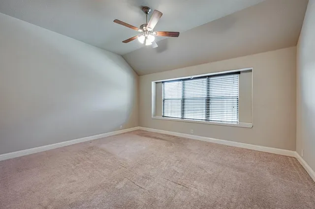 an empty room with chandelier fan and windows