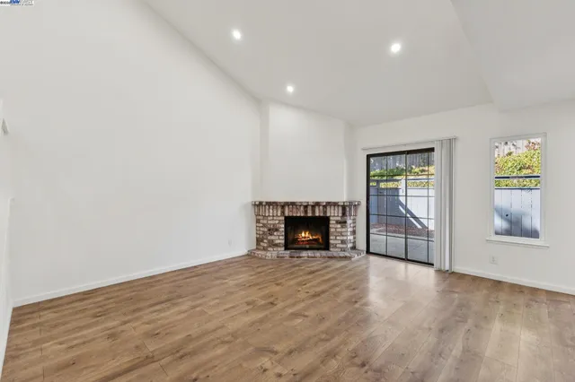 a view of empty room with wooden floor and fireplace