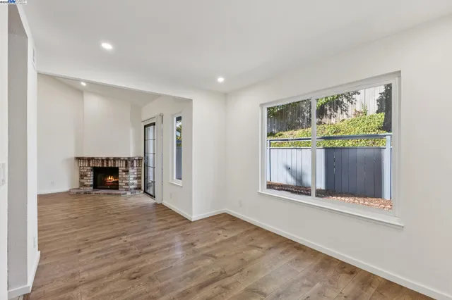 a view of empty room with fireplace and wooden floor