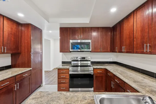 a kitchen with stainless steel appliances granite countertop wooden cabinets a stove top oven a sink and dishwasher