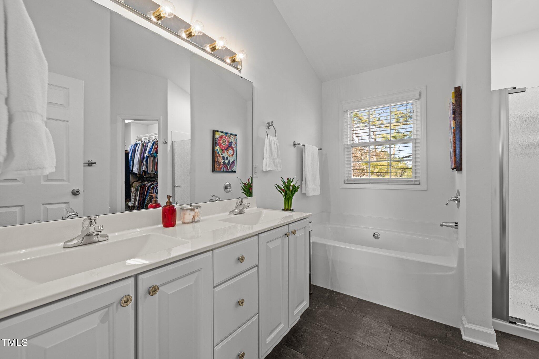 203 Stoney Drive Durham, NC 27703 - Photo 30 of 59 a bathroom with a double vanity sink a mirror and a bathtub