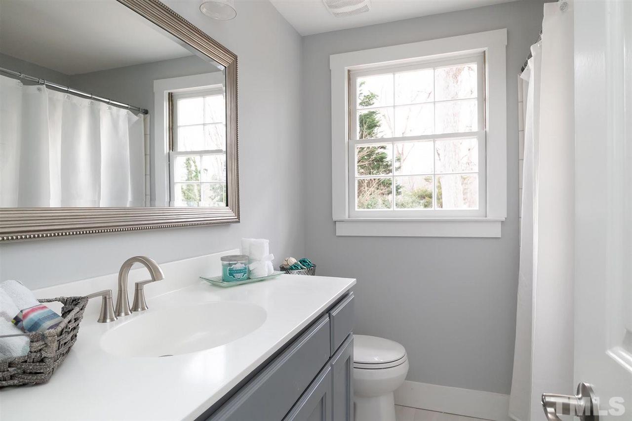 5501 Knollwood Road Raleigh, NC 27609 - Photo 20 of 25 a bathroom with a granite countertop toilet a sink a mirror and a window