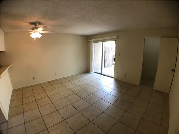 a view of an empty room and chandelier fan