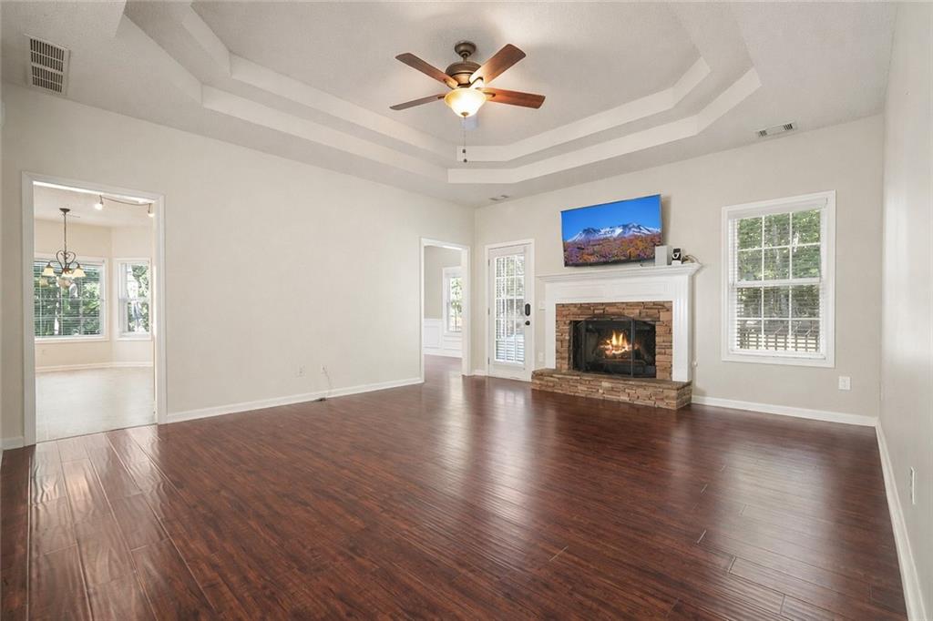 710 Bedford Trace Canton, GA 30114 - Photo 8 of 44 an empty room with windows a fireplace a ceiling fan and wooden floor