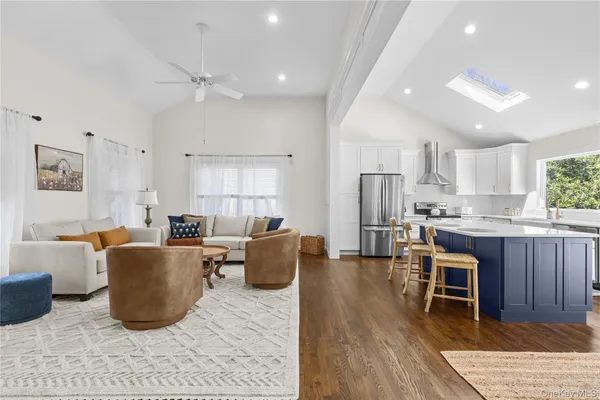 a living room with stainless steel appliances furniture a rug kitchen view and a chandelier