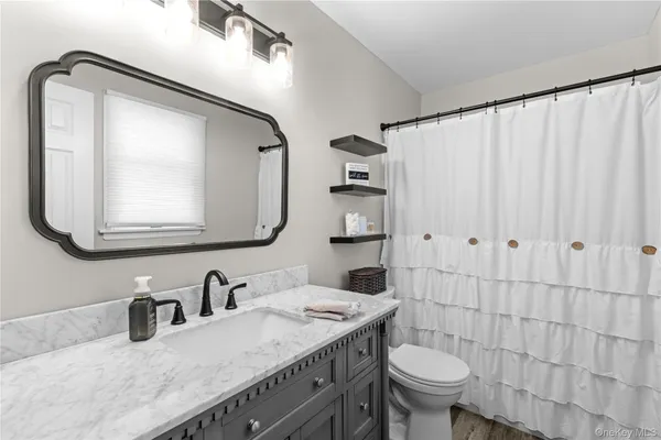 a bathroom with a granite countertop sink vanity mirror and toilet