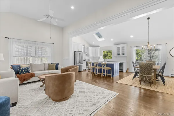 a living room with couches and kitchen view with wooden floor