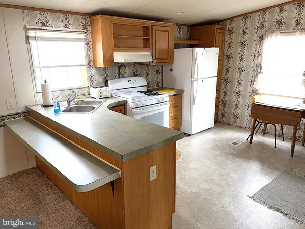 a kitchen with a refrigerator a stove a sink and a dining table with wooden floor