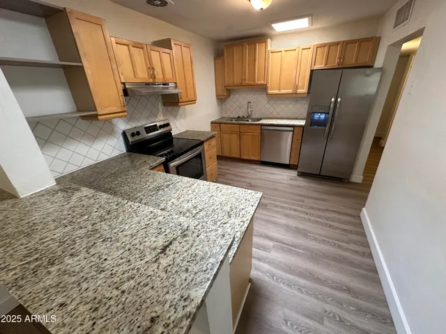 a kitchen with stainless steel appliances granite countertop a sink stove and refrigerator