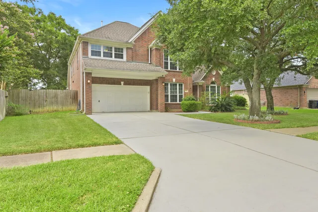 a front view of a house with a garden and trees