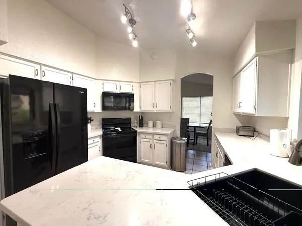 a kitchen with granite countertop a refrigerator stove and sink