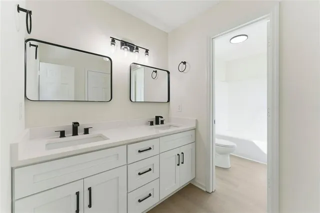 a bathroom with a toilet sink double vanity and mirror