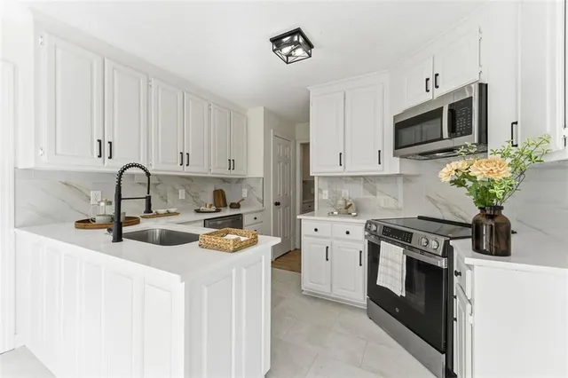 a kitchen with stainless steel appliances granite countertop white cabinets a stove a sink and dishwasher