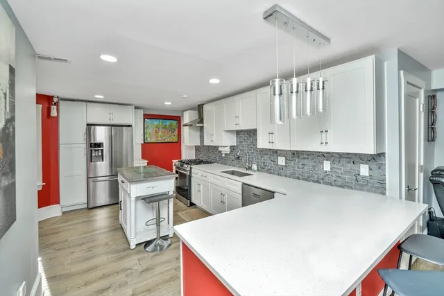a kitchen with a refrigerator a sink dishwasher and a stove with wooden floor