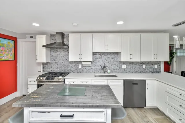 a kitchen with stainless steel appliances granite countertop a stove a sink and white cabinets
