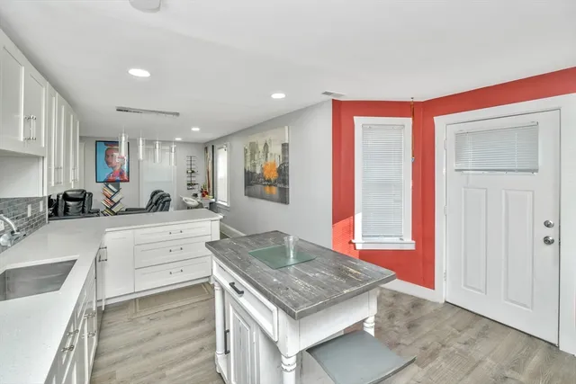 a kitchen with stainless steel appliances granite countertop a stove top oven a sink dishwasher and a refrigerator with wooden floor