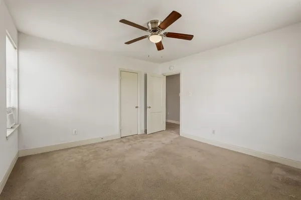 an empty room with closet and ceiling fan
